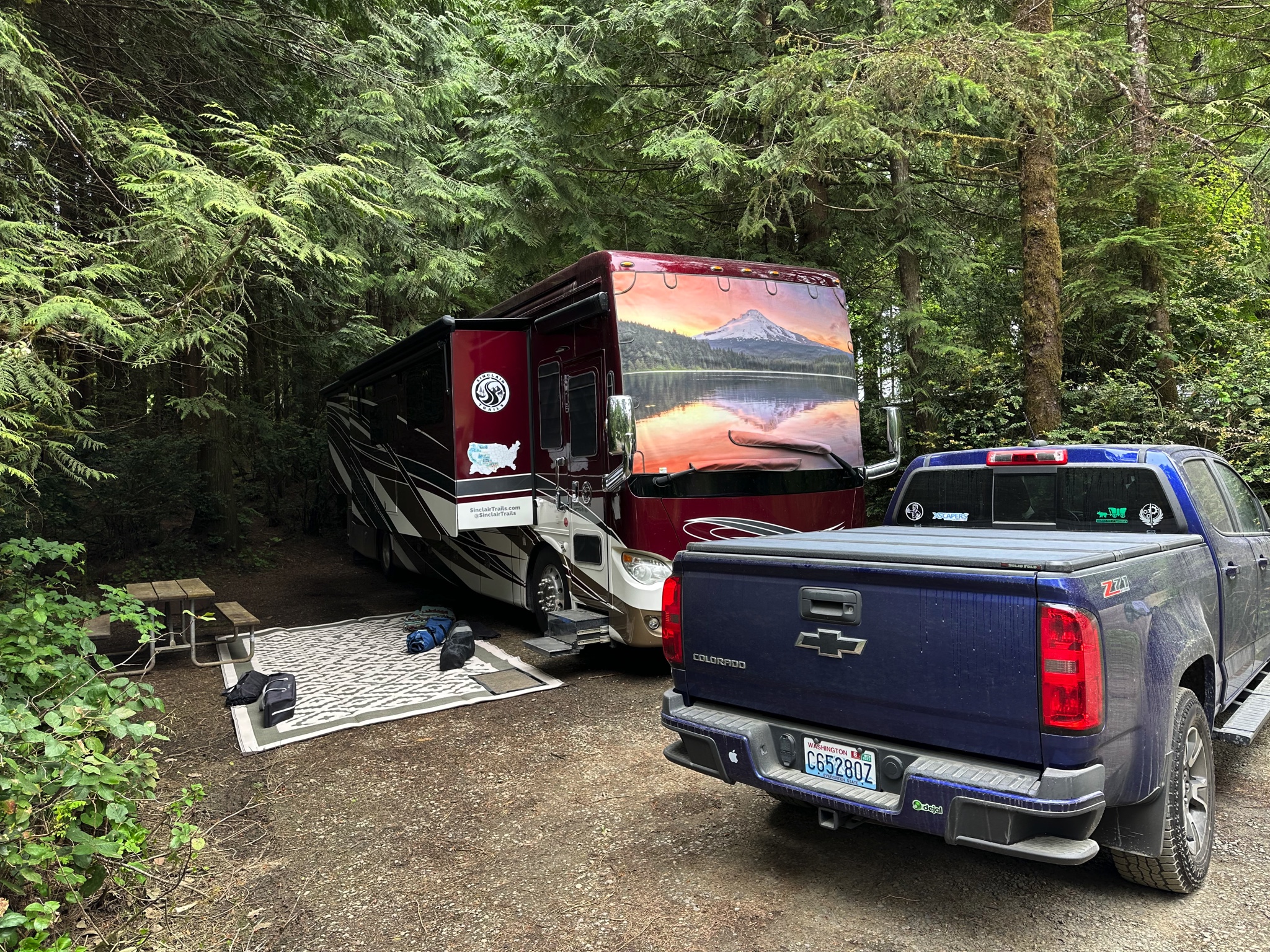 Motorhome and truck in a campsite tucked amongst trees